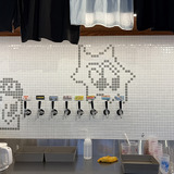 白いタイル壁にグレーのタイルパターンで描かれた「ロッキー」ほかキャラクター