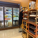 カウンター脇には缶ビールの冷蔵ケースとグッズコーナー