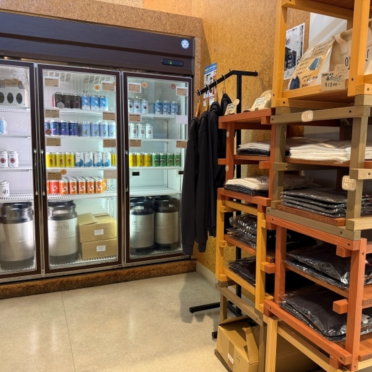 カウンター脇には缶ビールの冷蔵ケースとグッズコーナー